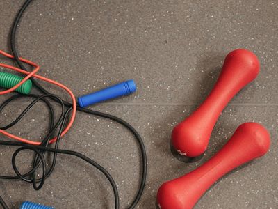 A pair of dumbbells and a jump rope on wood